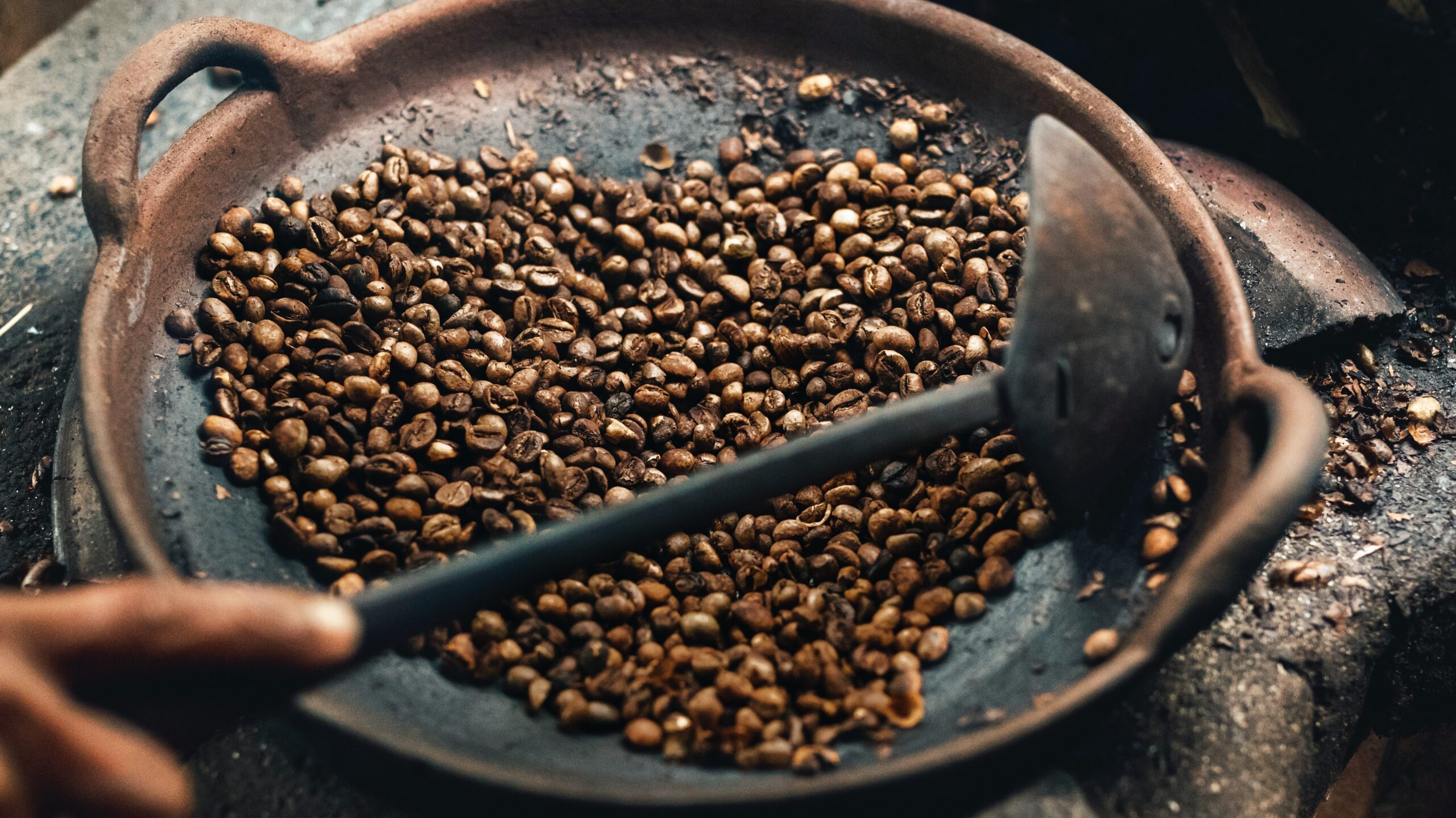 A person stirs roasting coffee beans.