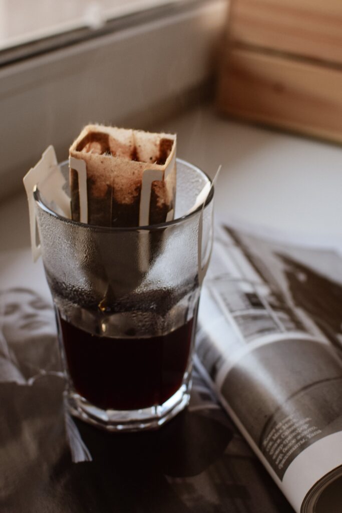 A cup of coffee with a travel-drip-coffee bag of the best coffee beans brewing