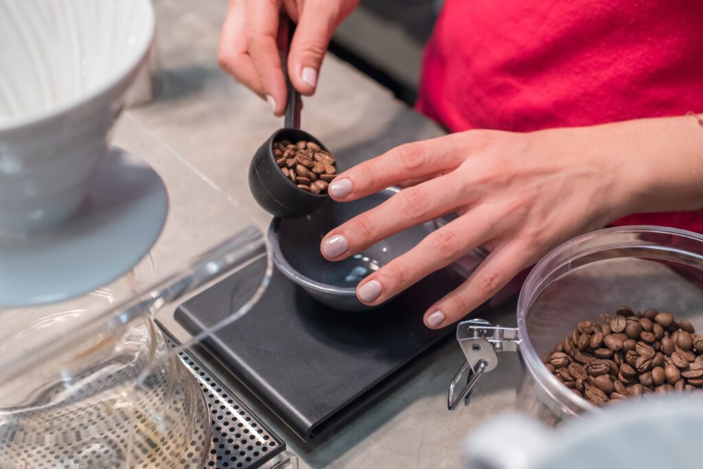A person is weighing coffee beans before grinding.